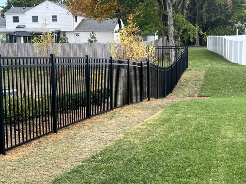 Black aluminum fence installed by Classic Fence with fall foliage behind it