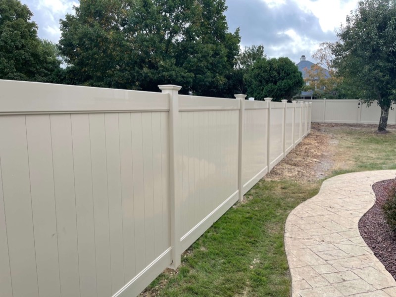 Tan vinyl privacy fence along a paver walkway, installed by Classic Fence